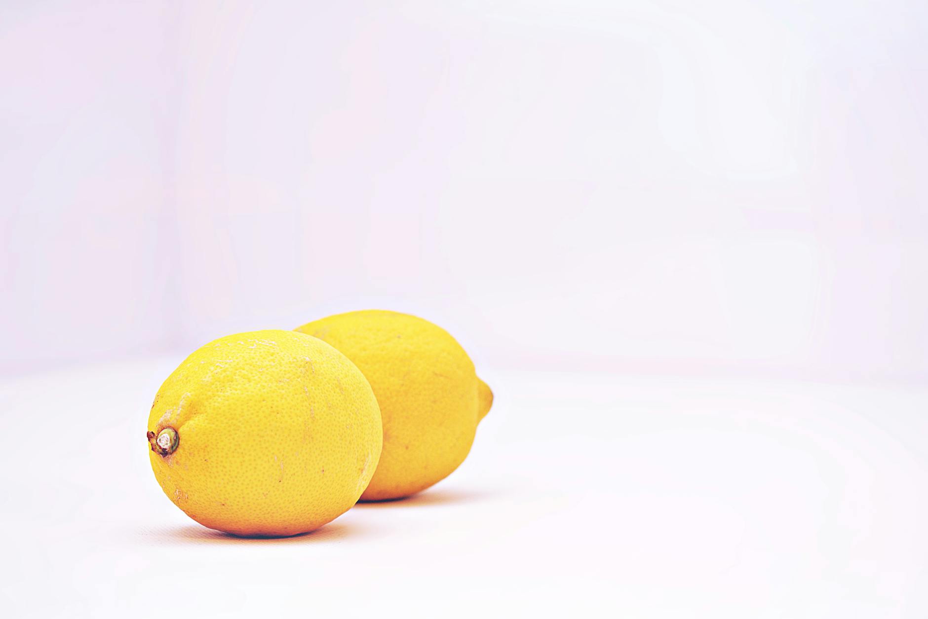 Due limoni vibranti posizionati su uno sfondo bianco minimalista, simboleggianti la freschezza e la semplicità della rinascita sessuale
