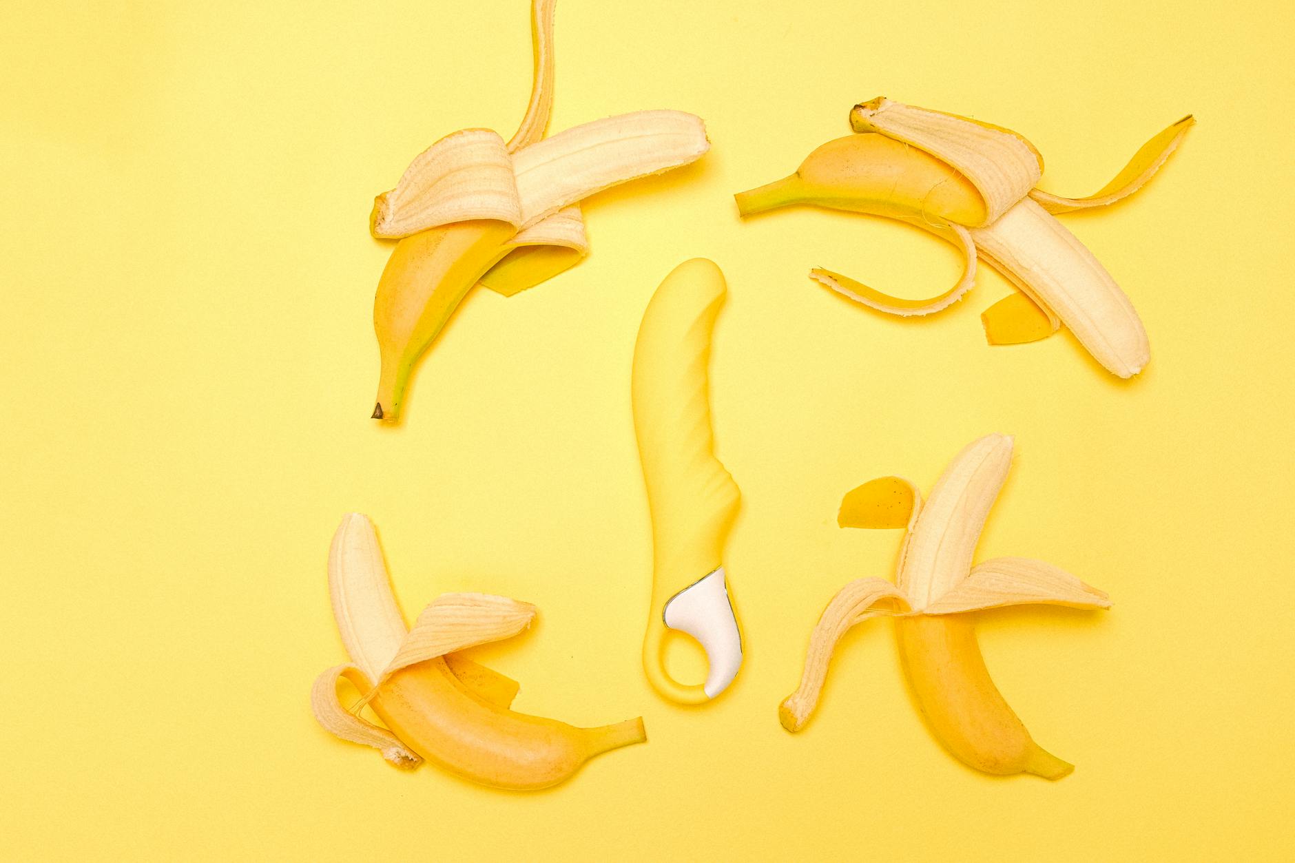 Yellow lemon vibrator surrounded by fresh lemons on a bright yellow surface, symbolizing gentle renewal