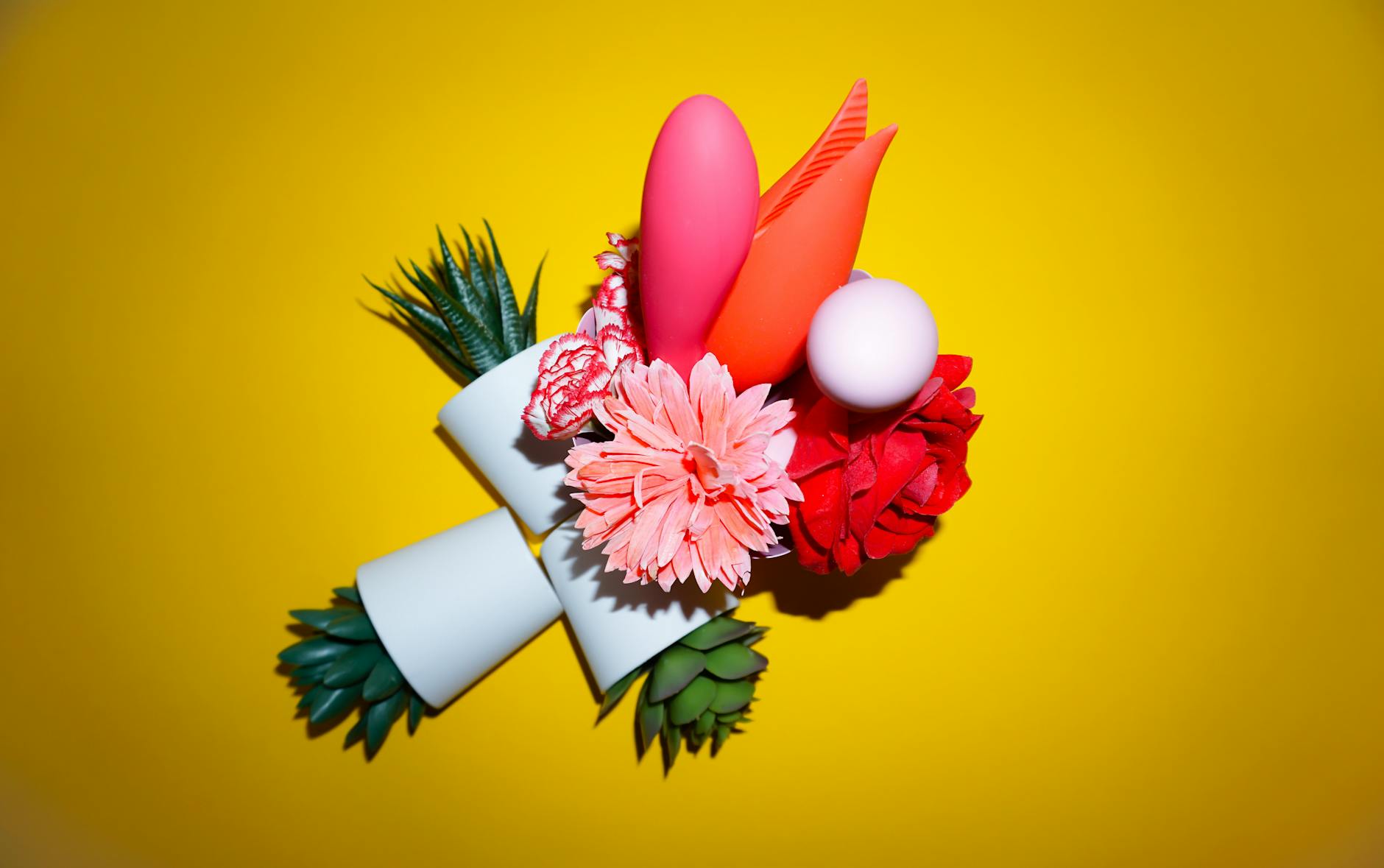 Two hands holding colorful silicone vibrators together, representing shared pleasure and intimate connection between partners.